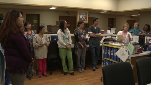 Members of a health care team huddle at the nurses' station 
