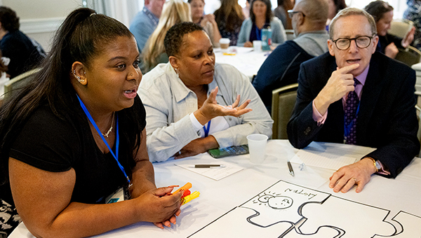 three people at a table with a puzzle diagram