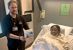 patient in bed with attendee holding a card