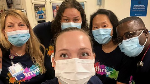 Hospital workers smiling from under their blue surgical face masks 