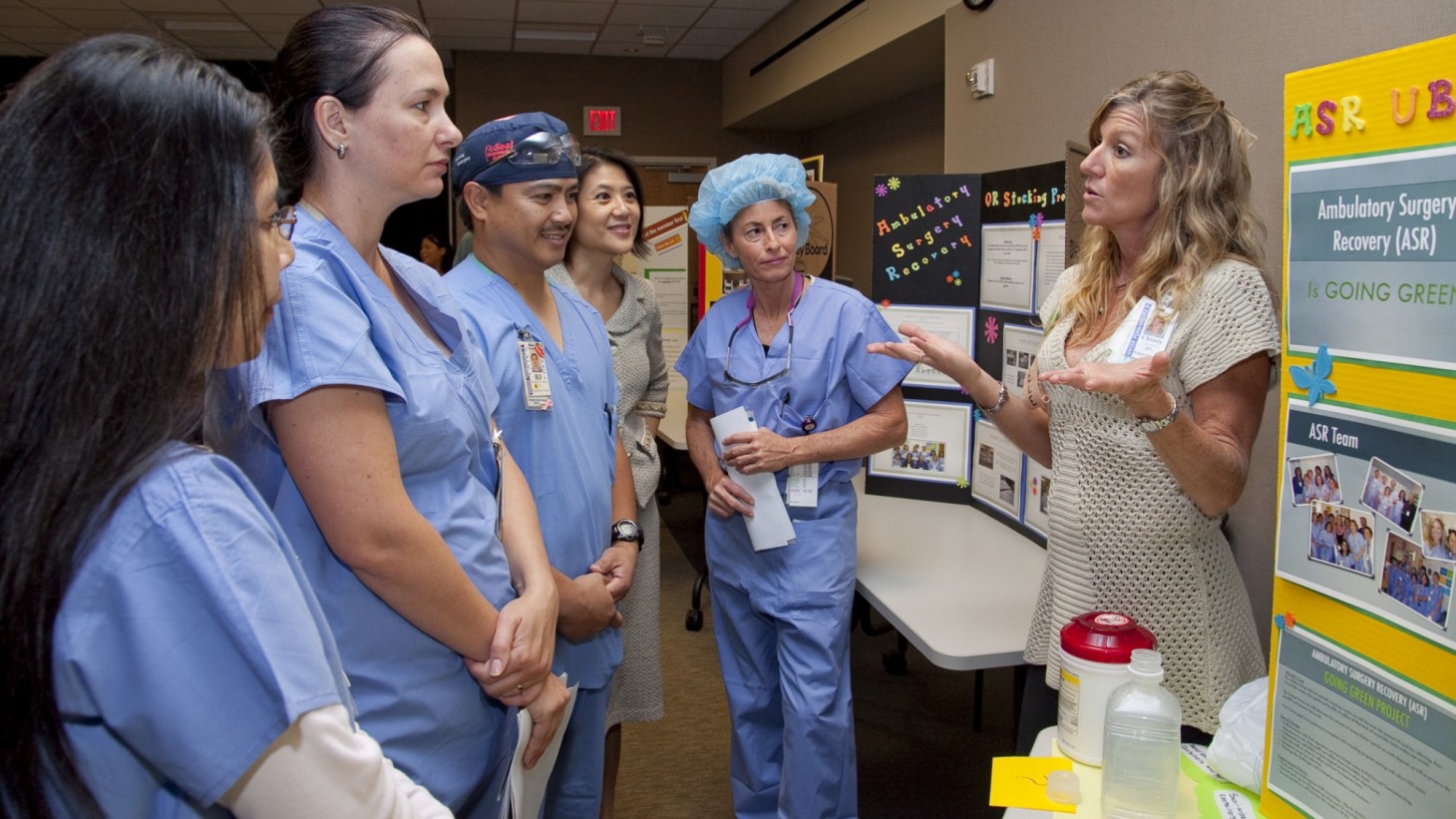 A woman explains a storyboard to several nurses gathered around her