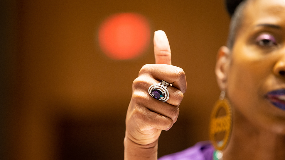 Woman wearing large ring, giving thumbs up