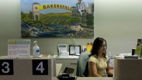 Receptionist at her desk under a painting of Bakersfield