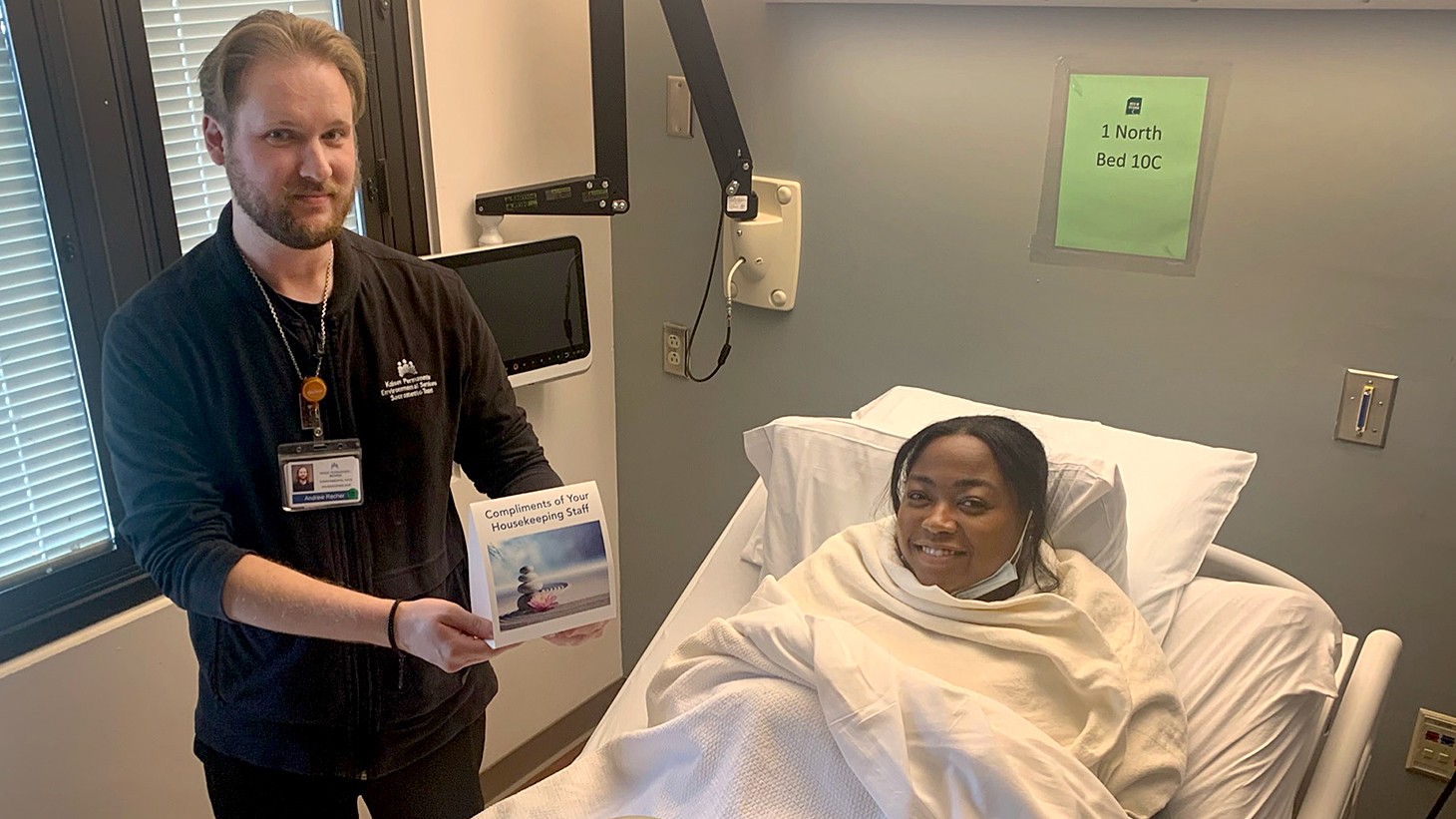 White man with beard showing a tent card to black woman in a hospital bed