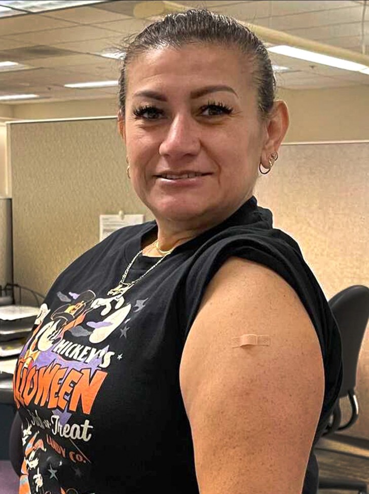 Woman wearing black t-shirt, with sleeve rolled up, revealing a bandaid on her arm